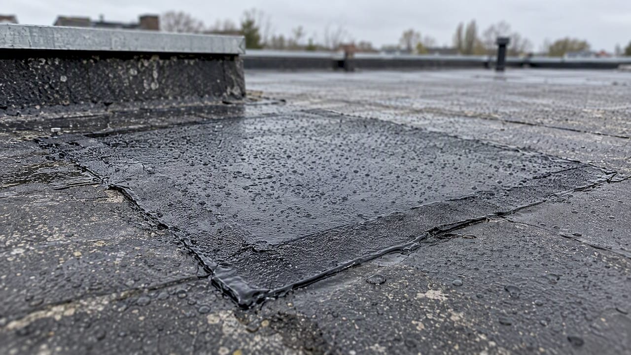 Bitumen reparatiepleister met regendruppels op het dak